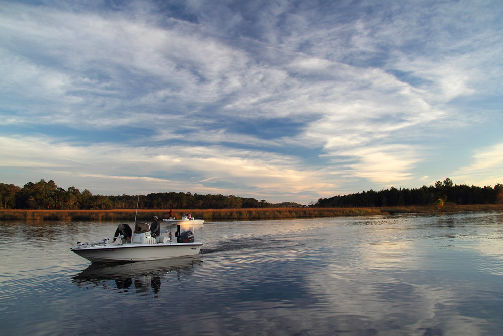 Wade fisherman fighting a flounder in a Texas marsh drain during the fall flounder run